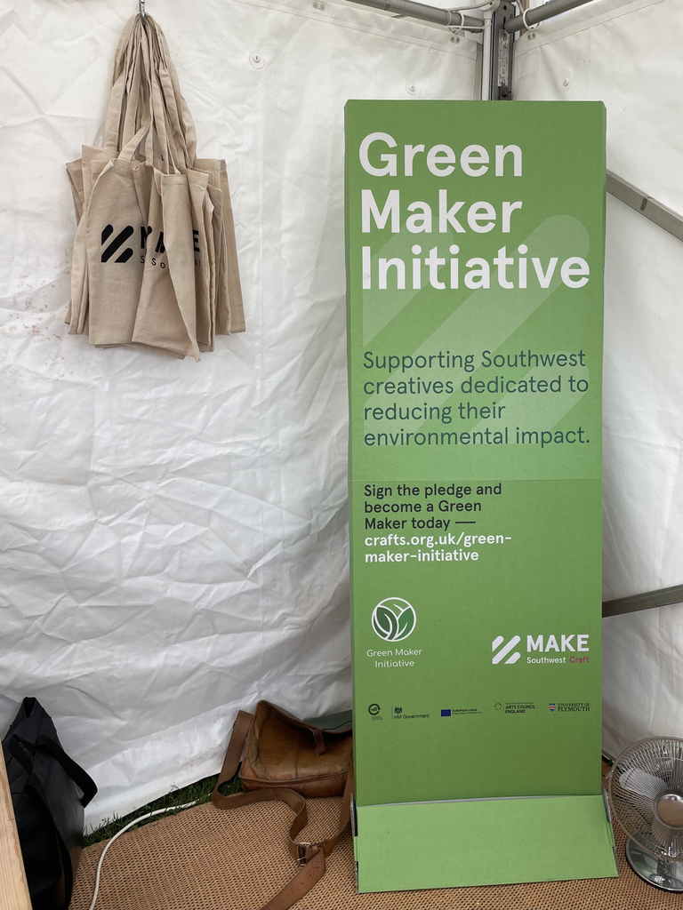 Picture of the Green Maker Initiative Banner at the MAKE Southwest stall. Full green-coloured banner on white background with
