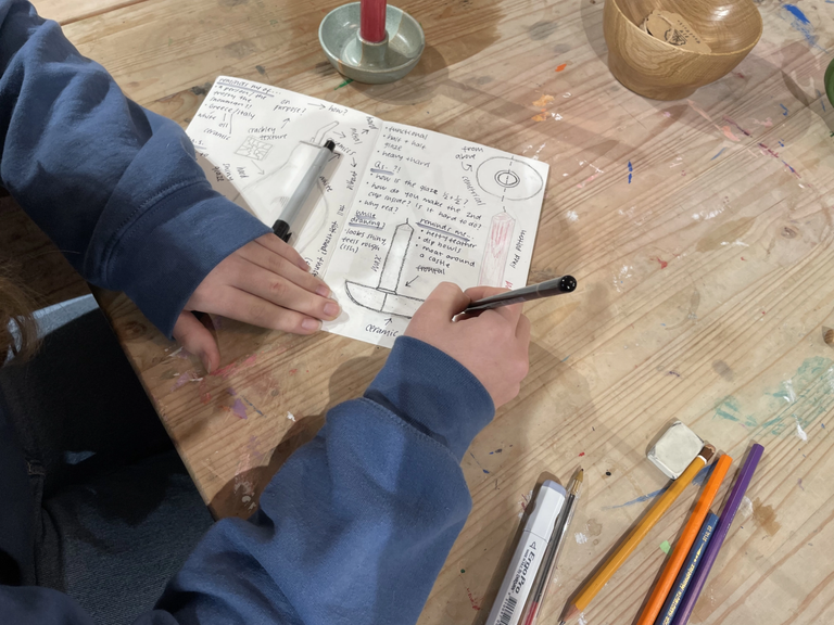 Hands holding markers drawing a ceramic candle holder